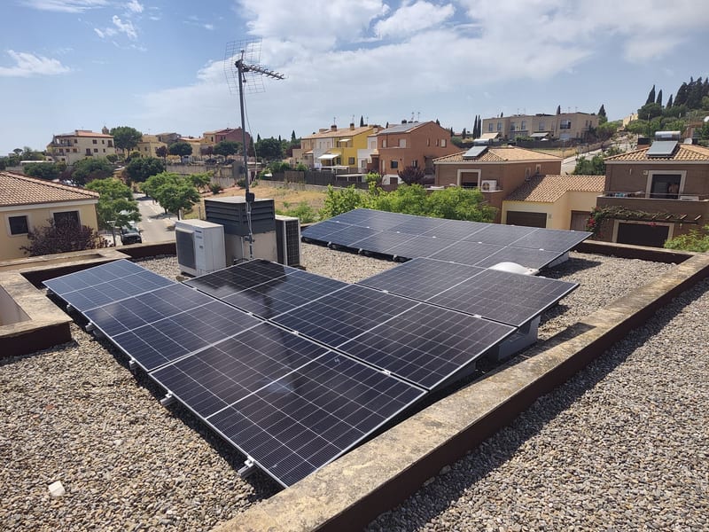Placas solares sobre cubierta plana de grava, junto a la máquina de aerotermia